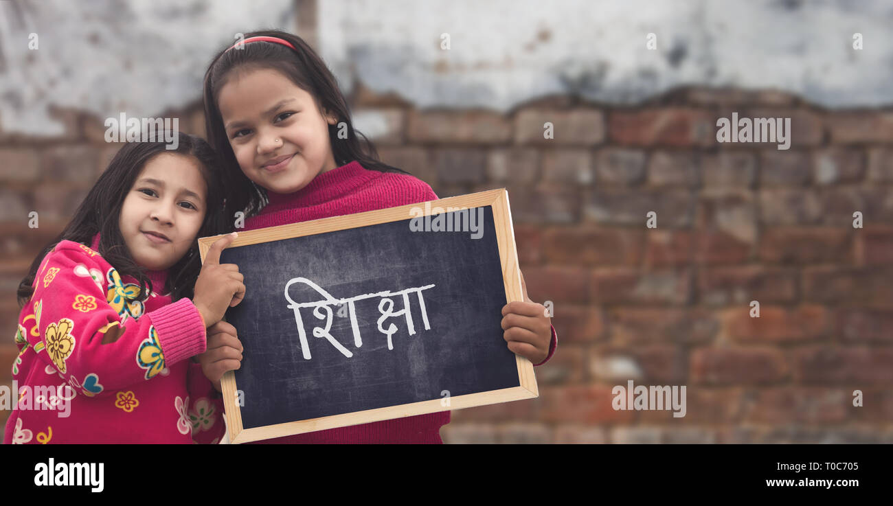 Adorable petit 6-8 ans et 8-10 ans filles indiennes smiling holding, tableau de l'éducation. Banque D'Images