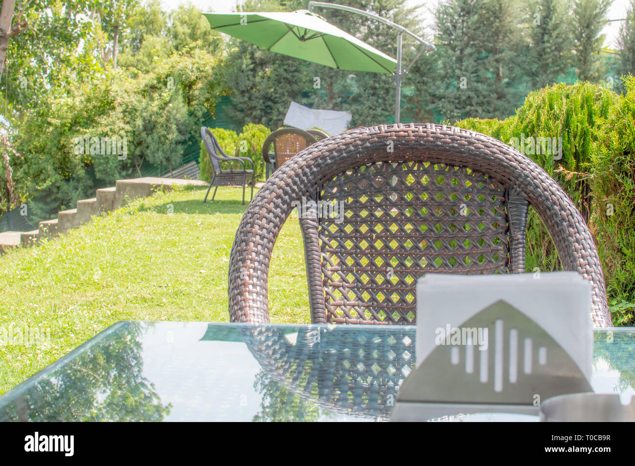 Une chaise avec une table et des tissus sur la table en verre dans un café avec ses plantes vertes luxuriantes Banque D'Images