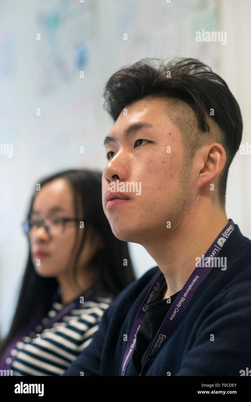 Les élèves et les étudiants dans une salle de classe dans un collège/université, d'être enseigné une leçon alors que dans la formation continue Banque D'Images