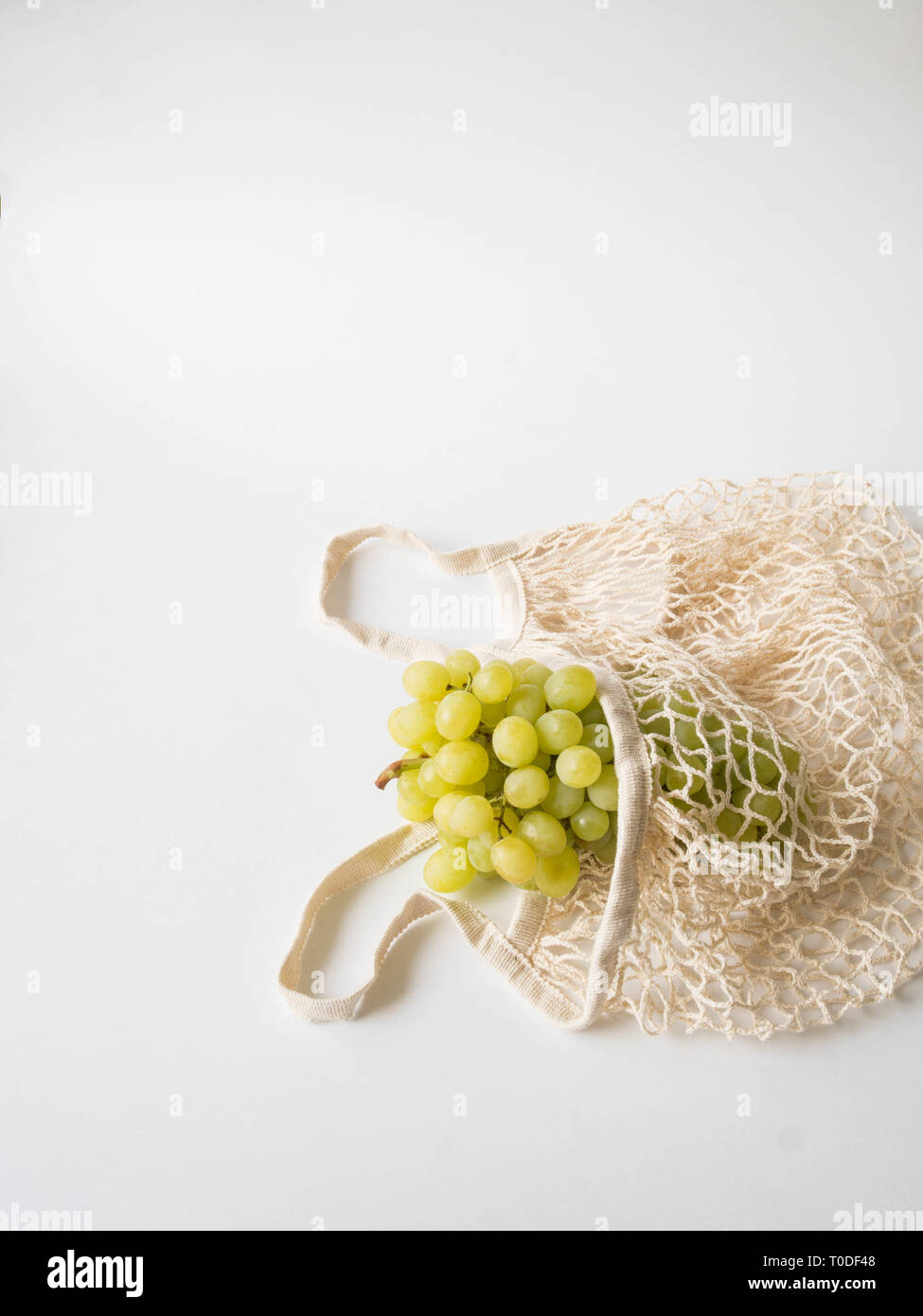 Eco-friendly beige panier de raisins sur un fond blanc. Sac de chaîne avec des fruits. Zéro déchets en plastique, pas de concept. Copy space Banque D'Images