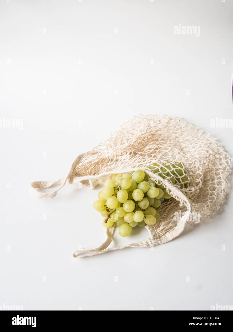 Eco-friendly beige panier de raisins sur un fond blanc. Sac de chaîne avec des fruits. Zéro déchets en plastique, pas de concept. Copy space Banque D'Images