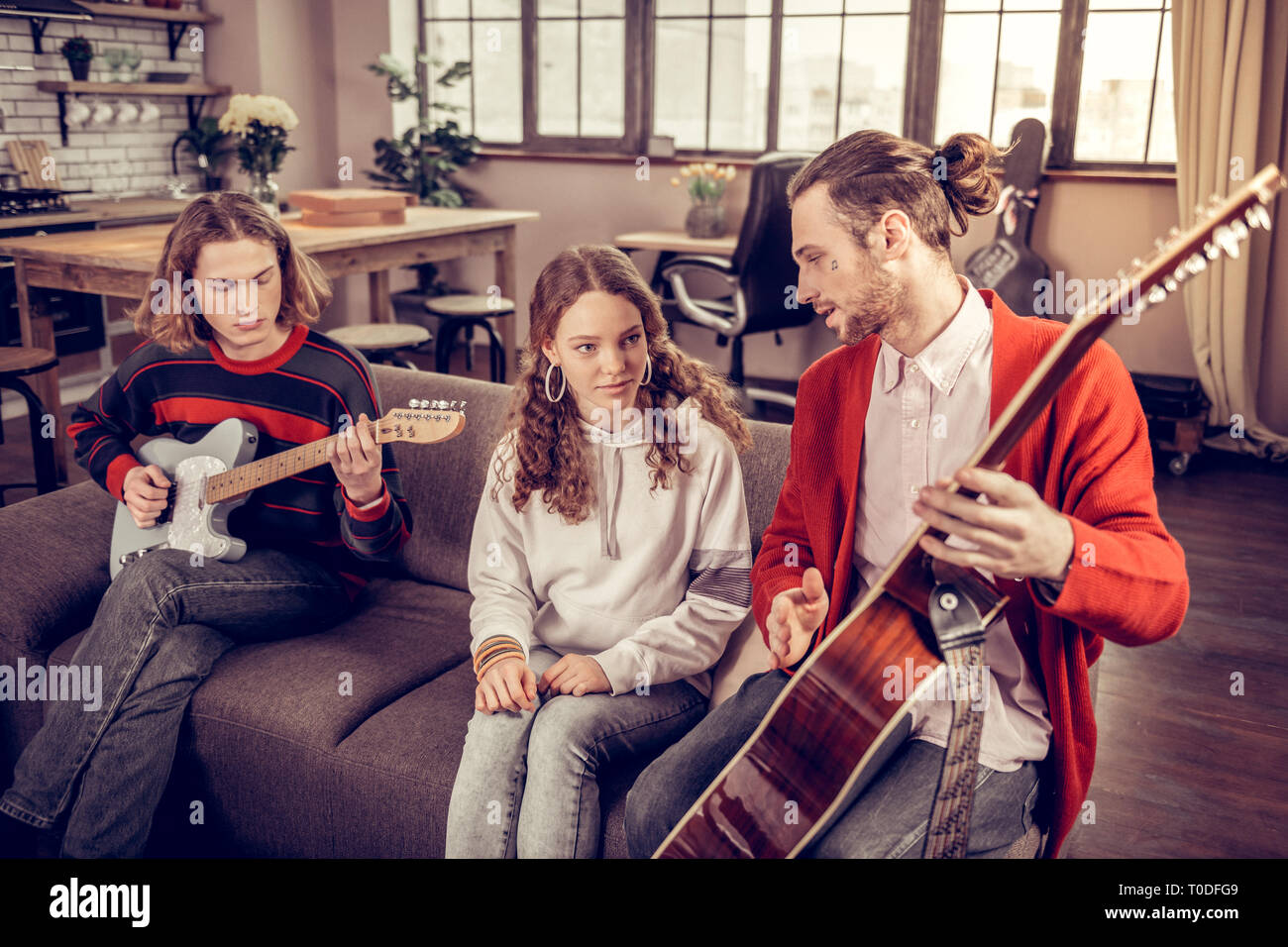 Curly girl looking at son frère aîné à la guitare Banque D'Images