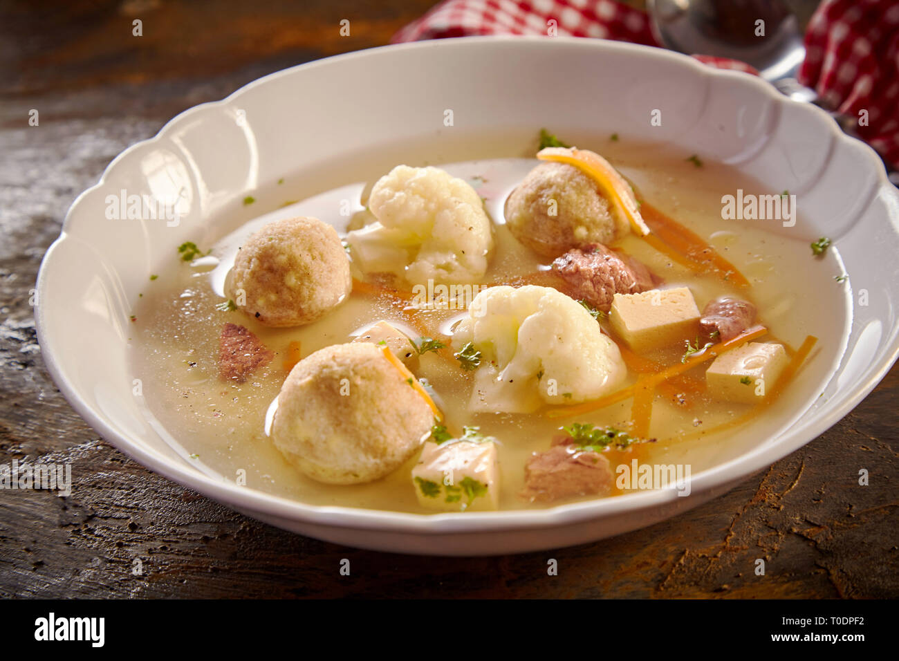 Au printemps gourmet avec bouillon de boulettes de moelle allemand, le chou-fleur et carottes en julienne garnie d'herbes dans un angle faible vue rapprochée Banque D'Images