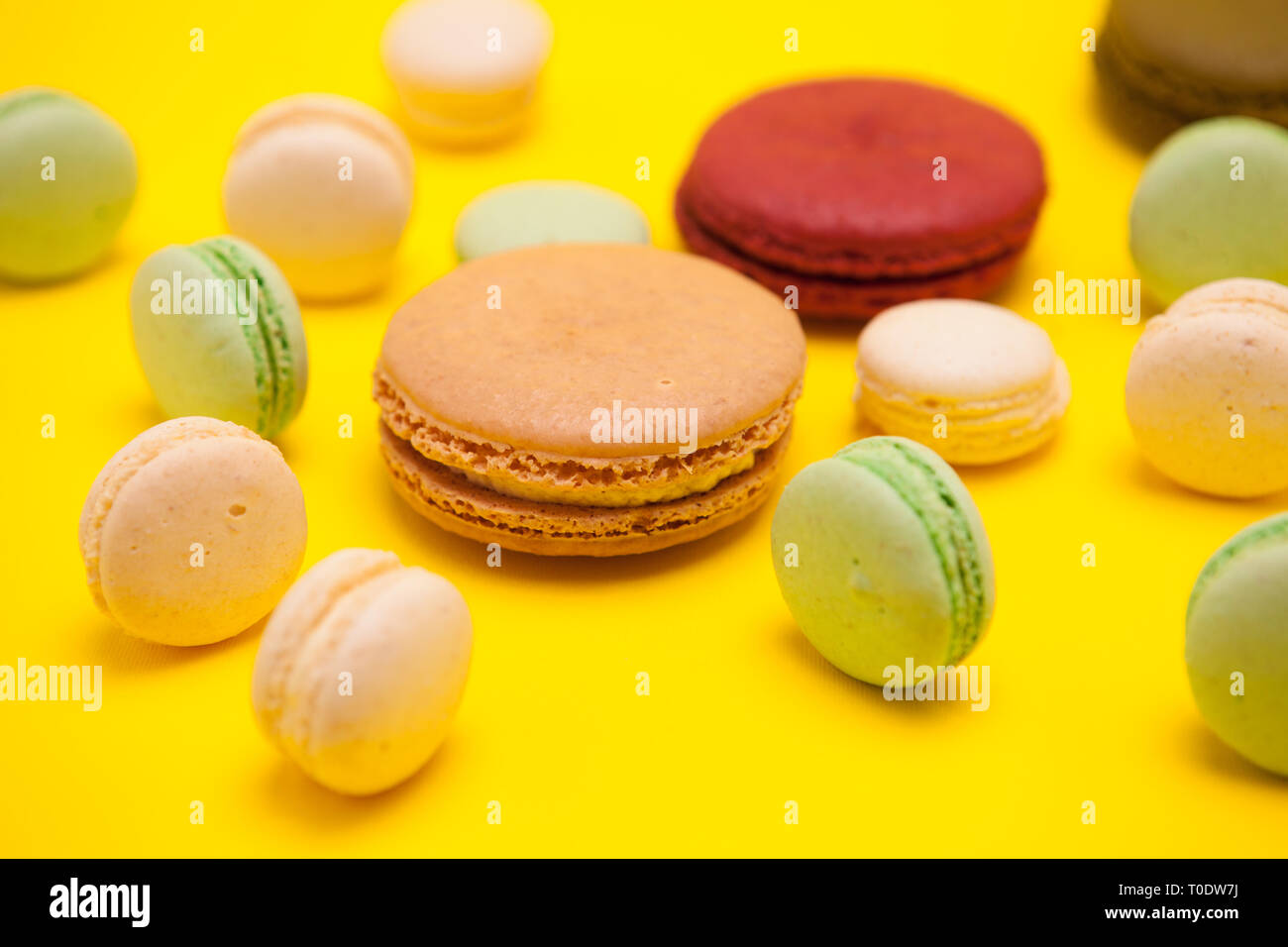 Différents schémas de macarons français colorés sur fond jaune. Desserts sucrés Banque D'Images