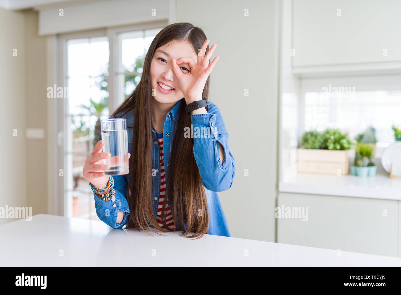 Belle asiatique femme à boire un verre d eau avec happy smiling face ok faire signe avec la main