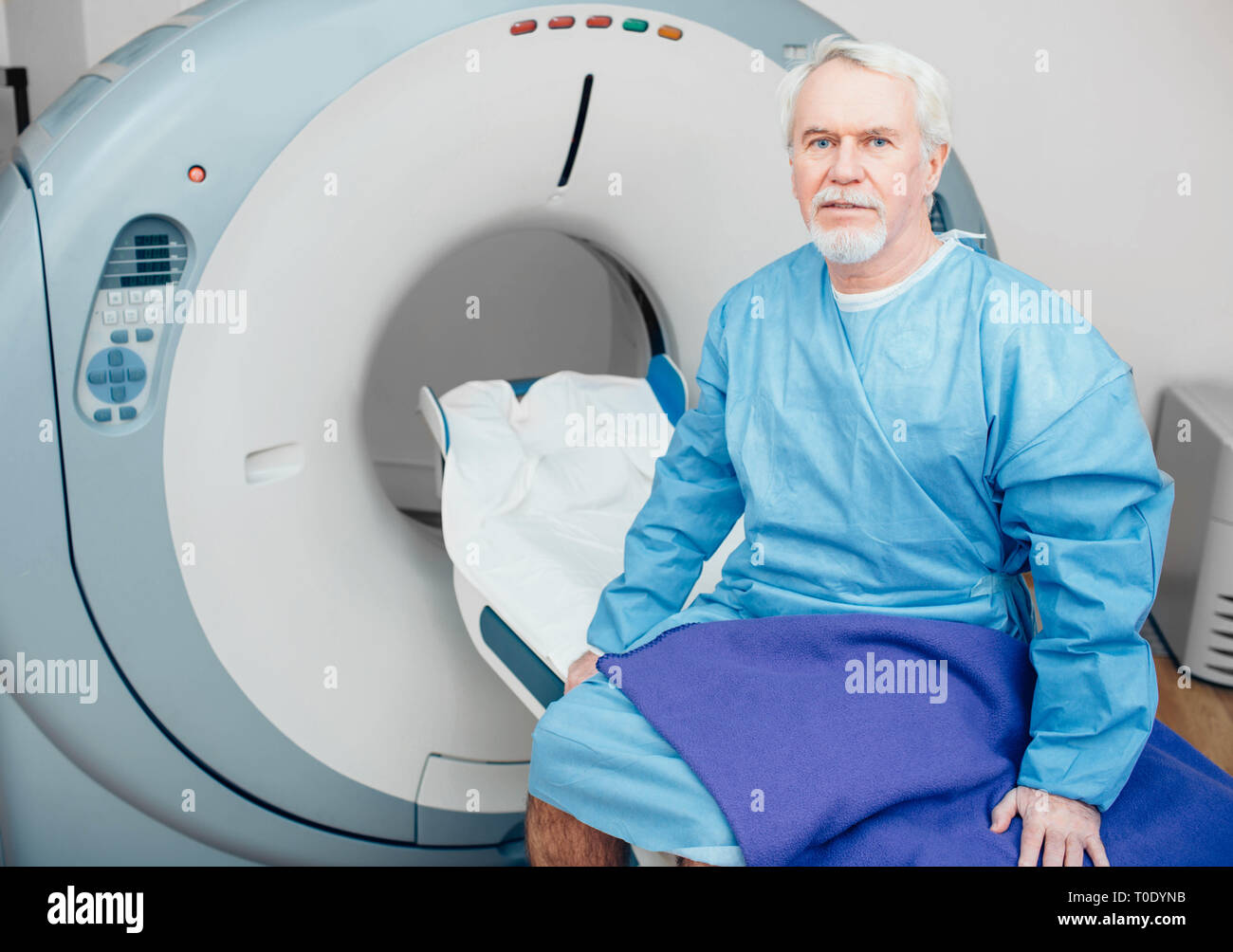 Senior man sitting on table du scanner. en attente de CT scan Banque D'Images