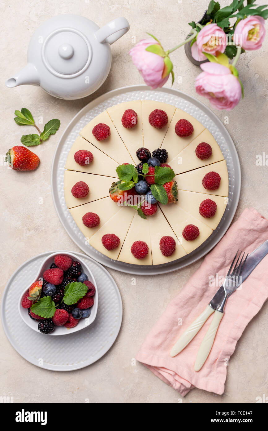 Fromage savoureux gâteau pour vacances avec framboise, fraise, théière, fleurs, fourchette, couteau et près de serviette.Concept de gâteau d'anniversaire. Haut de la vue, télévision lay Banque D'Images