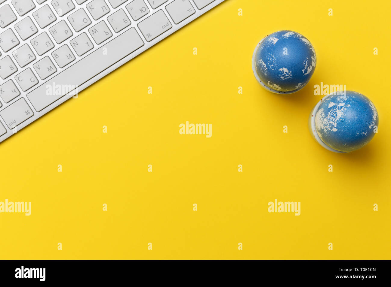Les oeufs de Pâques avec clavier bleu sur fond jaune. Concept de l'office de Pâques. Mise à plat, vue du dessus, l'espace libre pour le texte Banque D'Images Les oeufs de Pâques avec clavier bleu sur fond jaune. Concept de l'office de Pâques. Mise à plat, vue du dessus, l'espace libre pour le texte Banque D'Images