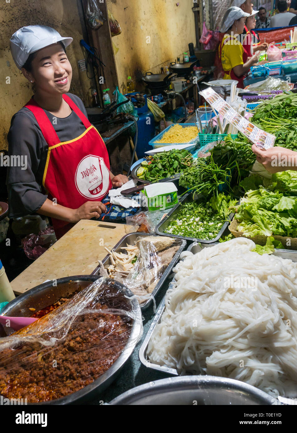 Smiling food titulaire de nuit rue du marché alimentaire avec des nouilles et des herbes, Luang Prabang, Laos, Asie Banque D'Images
