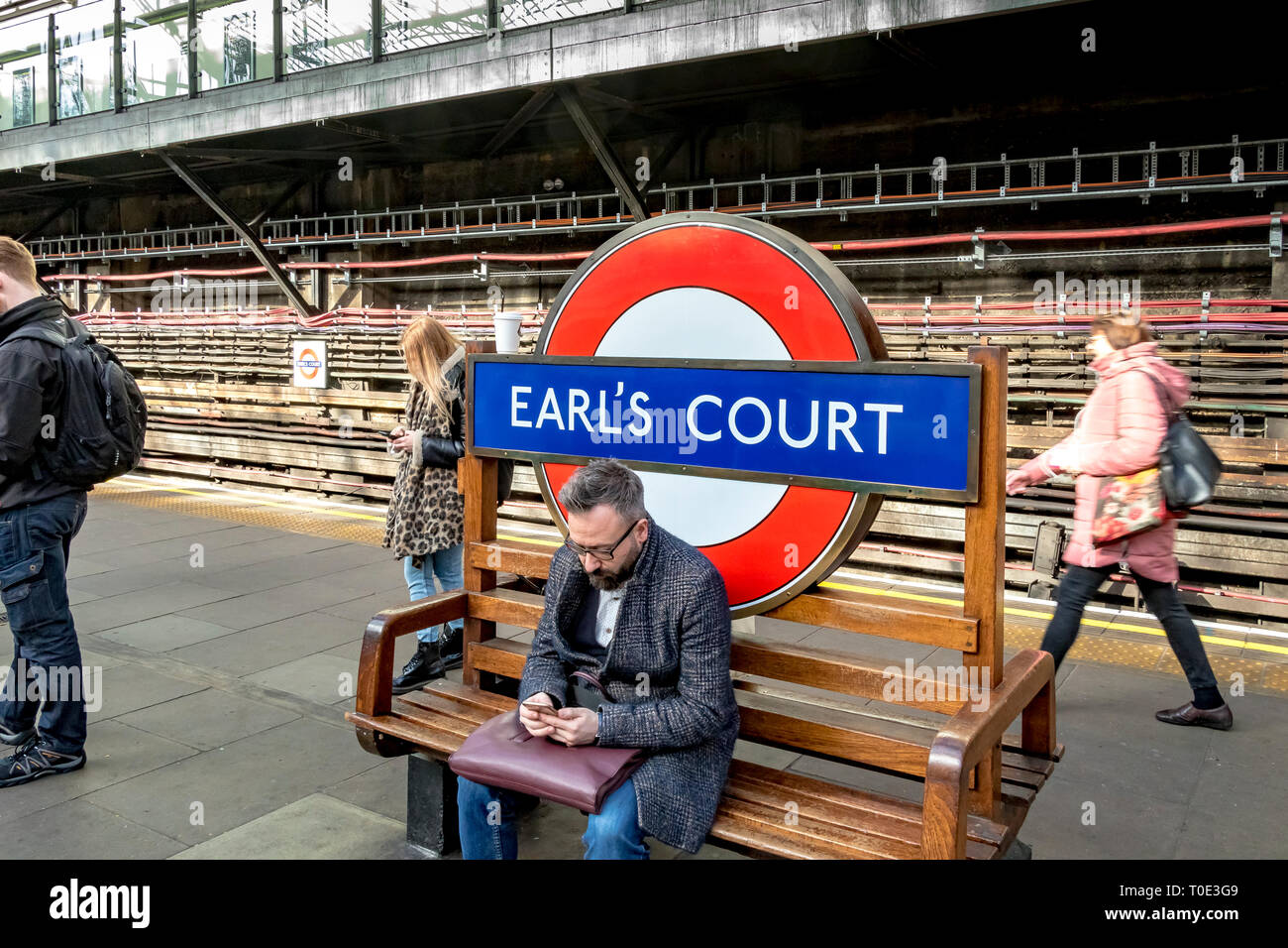 Un homme assis sur un banc à la station de métro Earls court, Londres, Royaume-Uni Banque D'Images