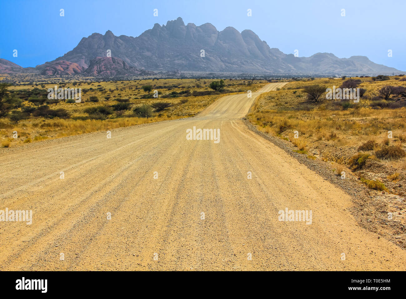Route de terre à Spitzkoppe en saison sèche, une montagne de granite rock formation situé entre Usakos et Swakopmund, dans le désert du Namib, Namibie. Banque D'Images