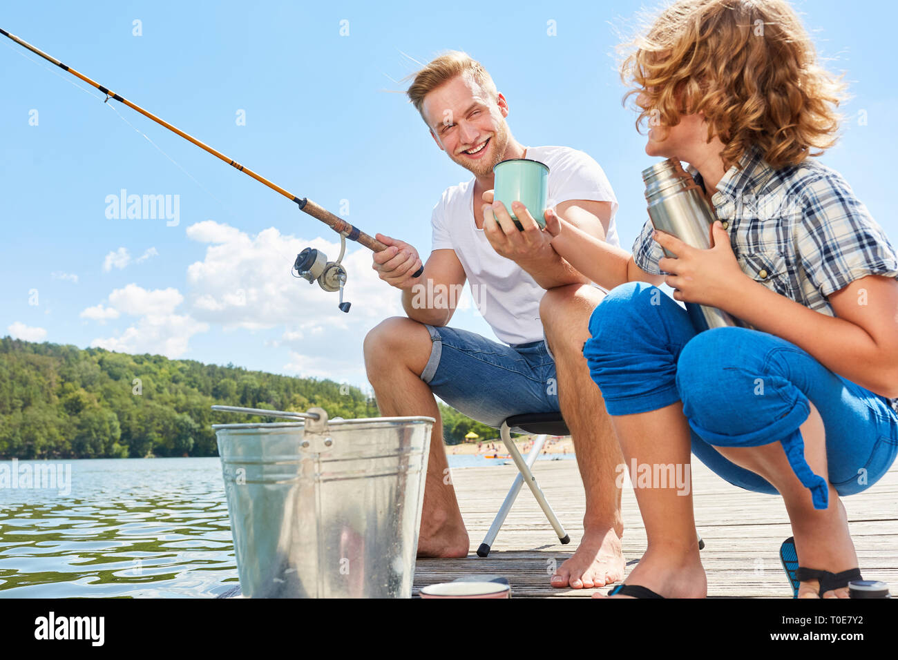 Le père et le fils de boire une tasse de café ensemble alors que la pêche sur le lac Banque D'Images Le père et le fils de boire une tasse de café ensemble alors que la pêche sur le lac Banque D'Images