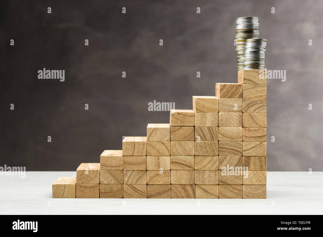 Concept de croissance. Graphique avec marches en bois sur fond gris avec pile de pièces sur le dessus. Banque D'Images