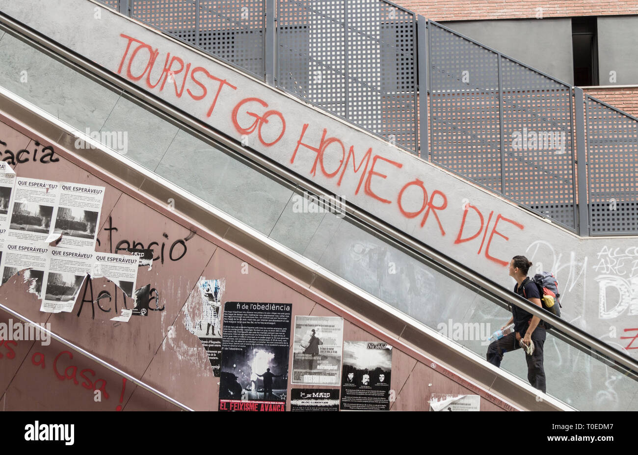 'Tourist Go home ou die' au mur près de l'escalier mécanique à Barcelone, Espagne. Concept de coronavirus... Banque D'Images
