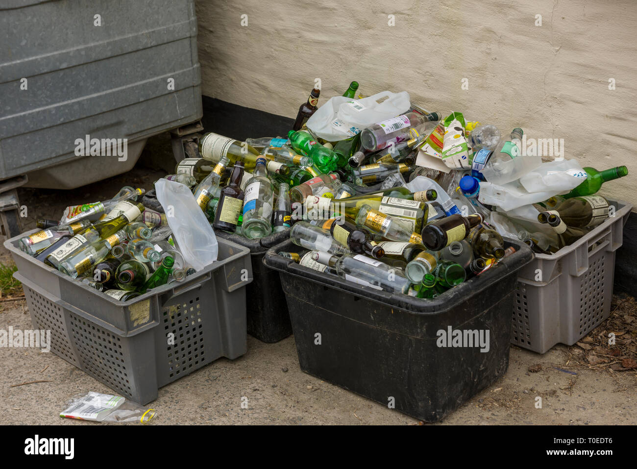 Les boîtes en plastique contenant de recyclage débordant et bouteilles en verre. Banque D'Images