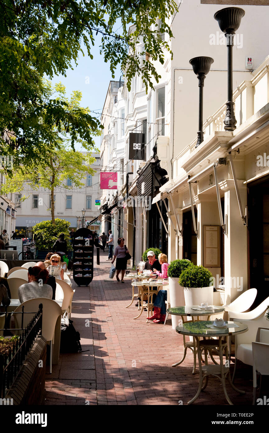 Les gens assis à l'extérieur d'un restaurant dans les ruelles de la ville balnéaire de Brighton, Sussex, Angleterre. Banque D'Images