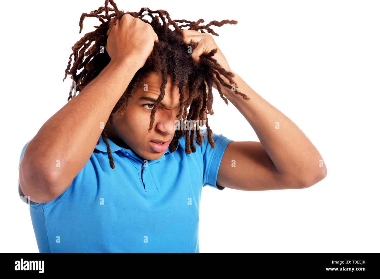 Jeune homme tirant ses cheveux contre fond blanc Banque D'Images