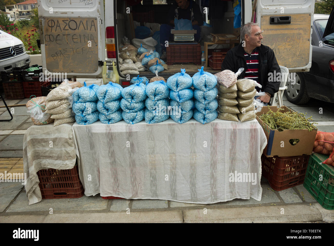 Exposant grec assis sur une chaise en attendant de vendre sa récolte de haricots beurre aux clients lors de l'assemblée annuelle du festival de châtaignes. Leivadi, Grèce Banque D'Images