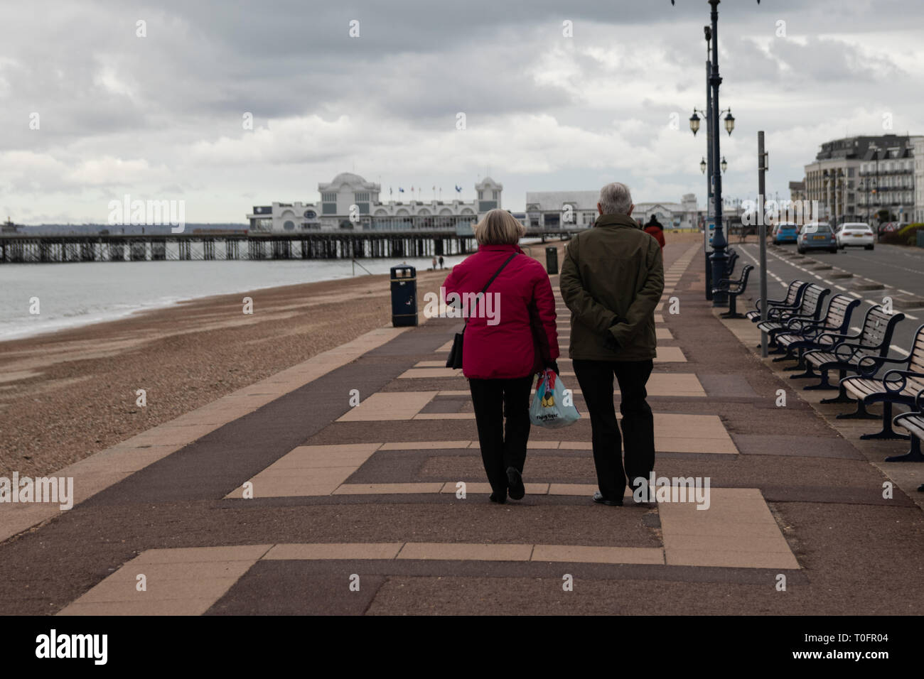 Un couple en train de marcher le long de la promenade de la plage de Southsea sur un jour froid et venteux mars Banque D'Images