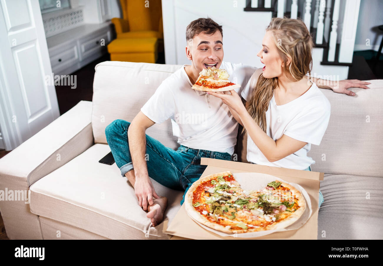 Belle blonde Woman feeding copain avec pizza Banque D'Images