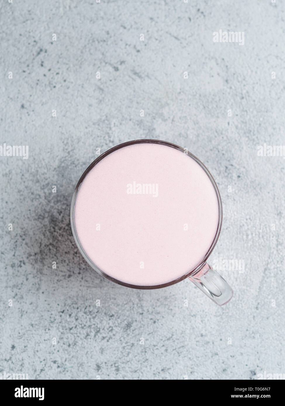 Boisson à la mode : pink latte. Betterave rouge ou framboise cappuccino ou latte dans verre tasse sur fond de ciment gris. L'espace de copie pour le texte. La verticale. Vue de dessus ou de télévision. Banque D'Images
