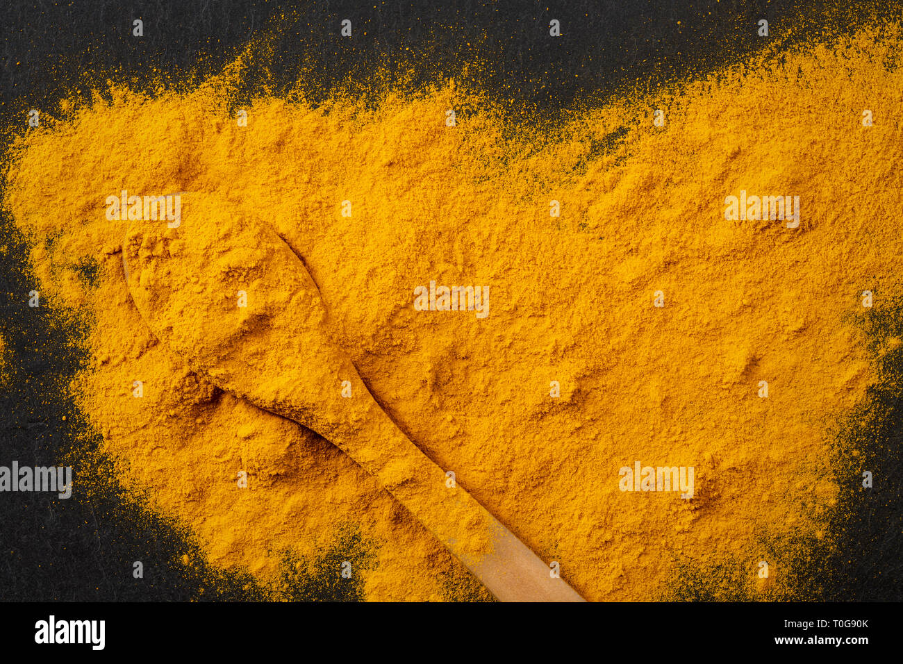 Des tas d'épices curcuma curcuma avec cuillère sur fond ardoise noir foncé, vue du dessus Banque D'Images