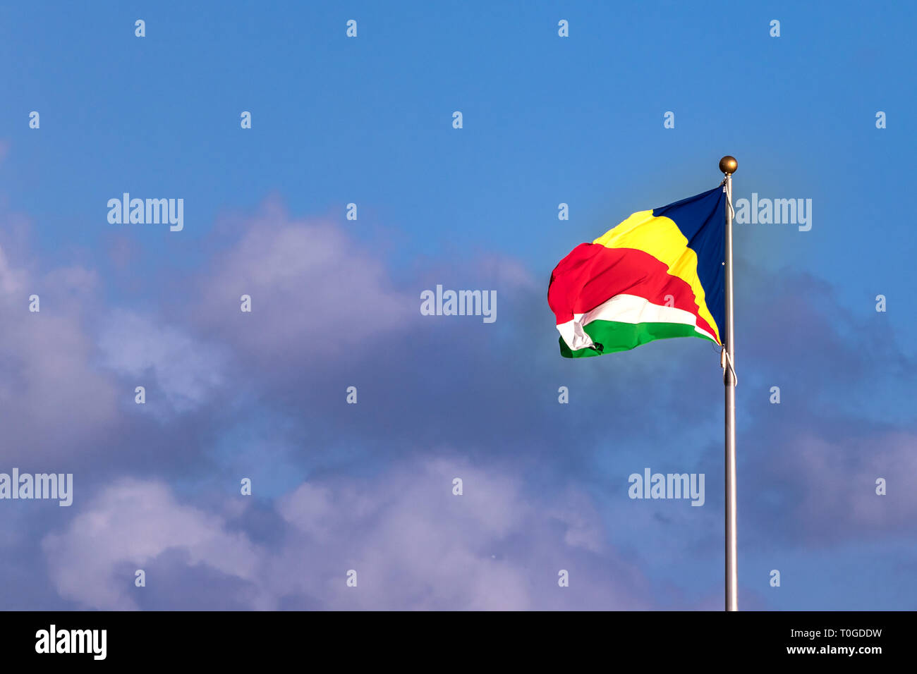 Le drapeau des Seychelles sur un ciel bleu avec des nuages. Banque D'Images