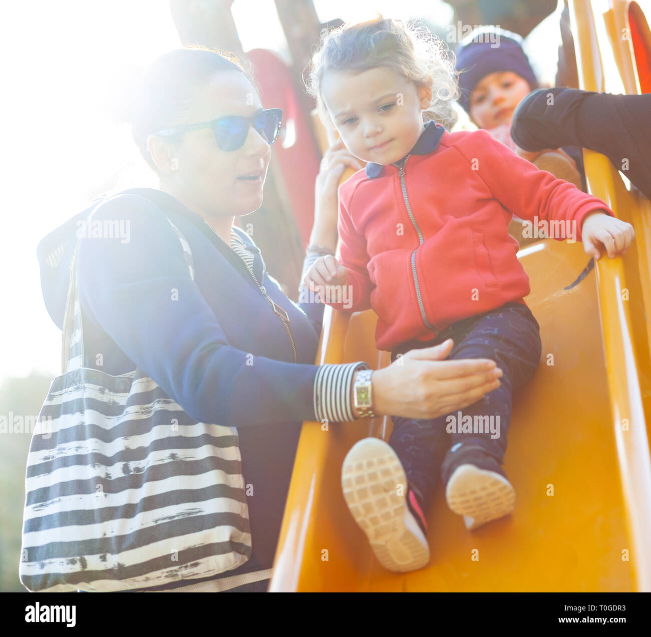 Tante et neveu jouer sur la diapositive au parc dans une journée de printemps. Banque D'Images