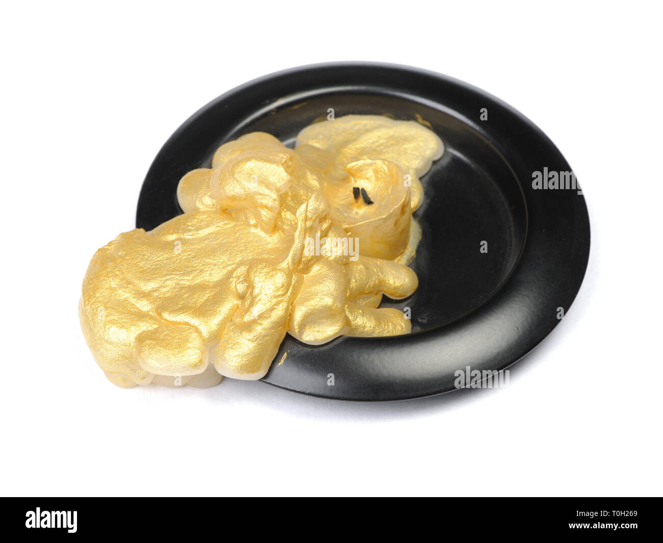 Vieille bougie de cire d'or sur un socle noir sur fond blanc isolé Banque D'Images