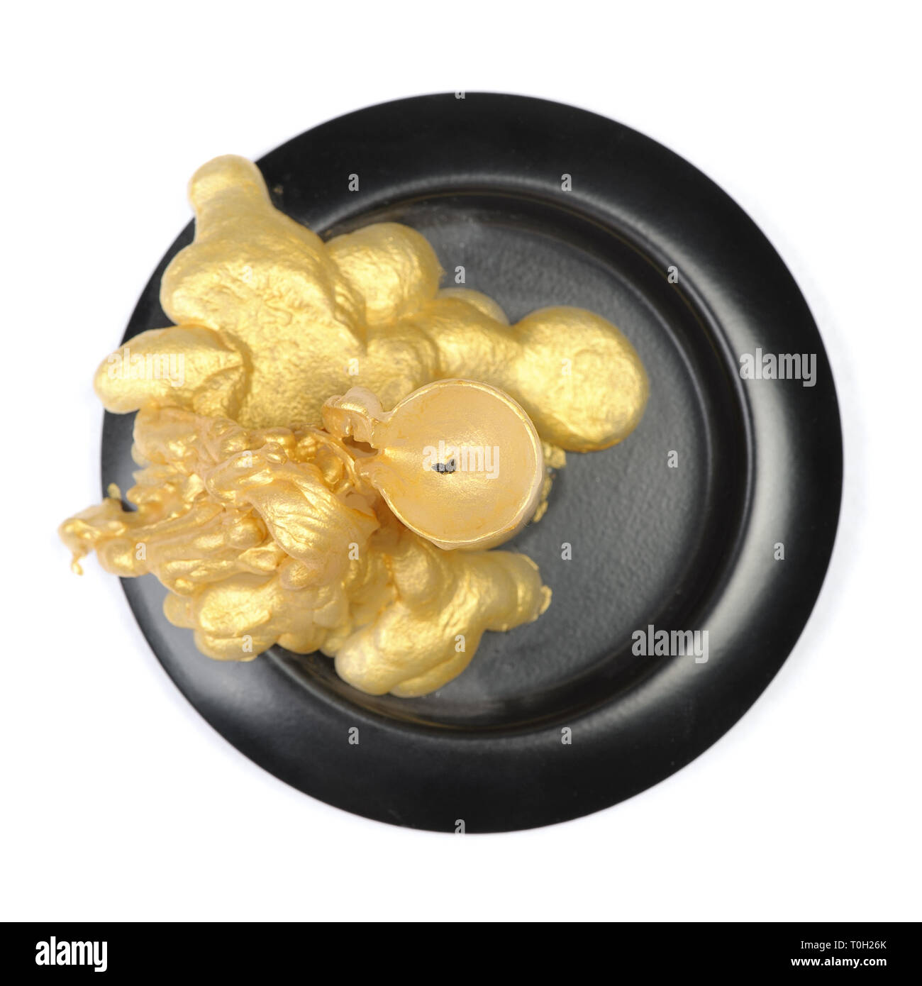 Vieille bougie de cire d'or sur un socle noir sur fond blanc isolé Banque D'Images