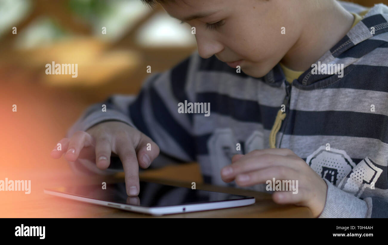 Garçon joue avec intérêt sur la tablette, s'amuser Banque D'Images