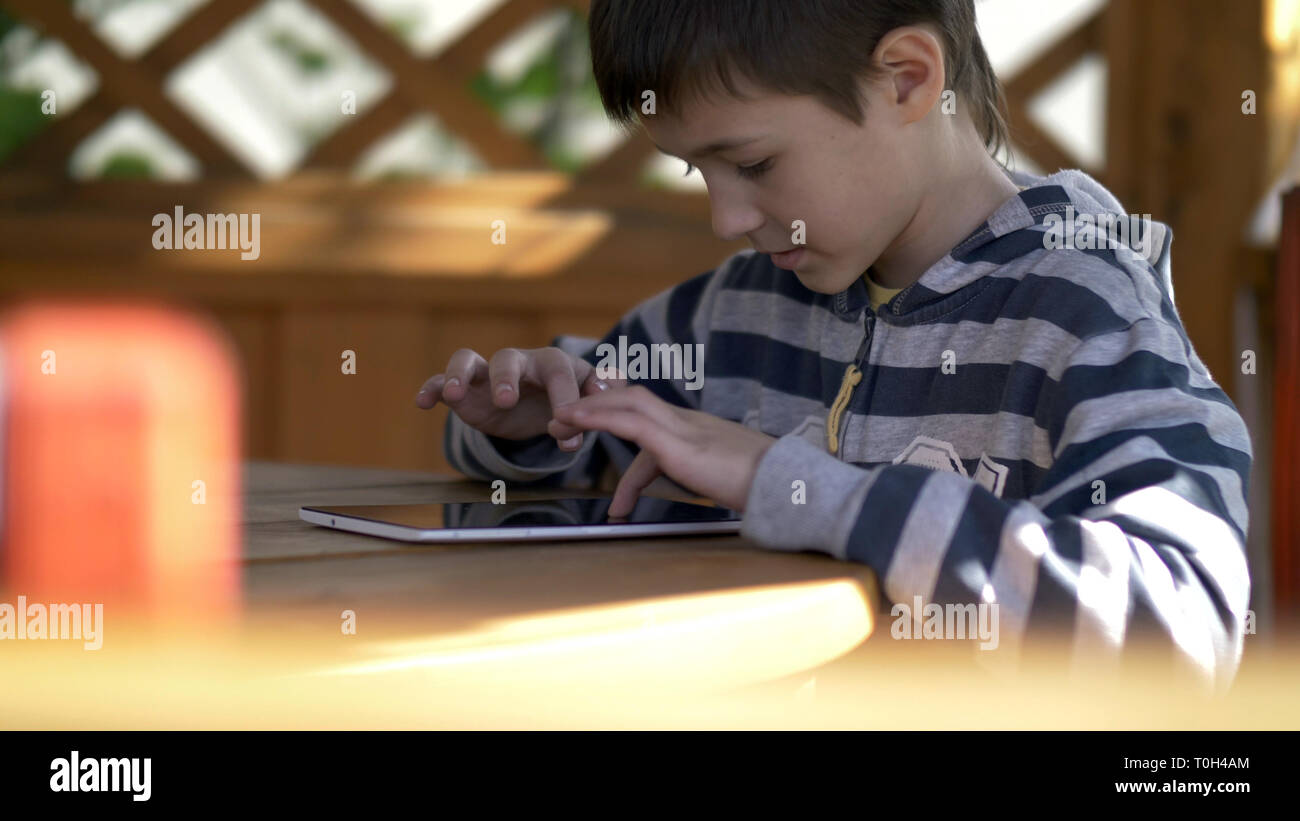 Garçon joue avec intérêt sur la tablette, s'amuser Banque D'Images