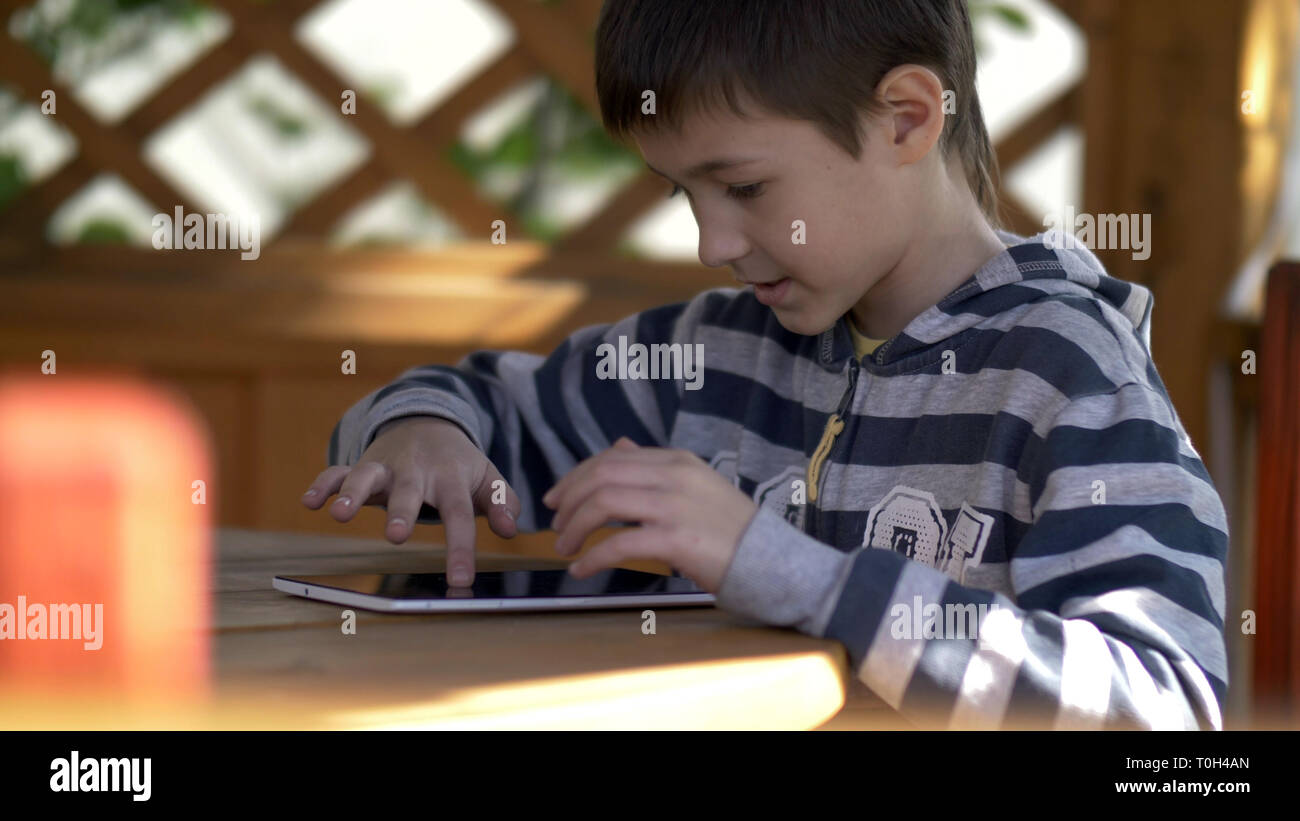 Garçon joue avec intérêt sur la tablette, s'amuser Banque D'Images
