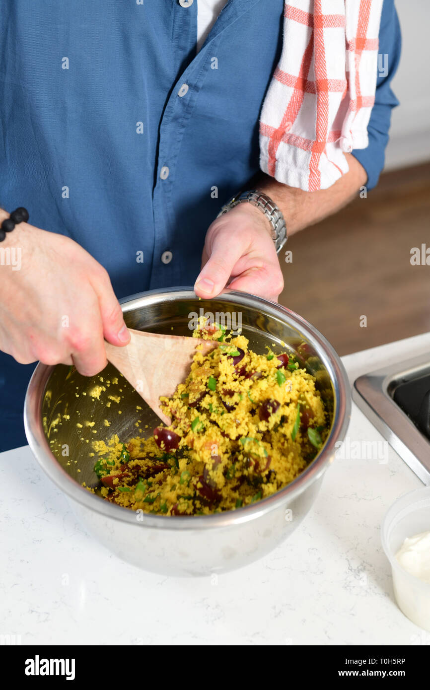 L'homme alimentaire faisant une salade de couscous dans un plat de cuisine à domicile Banque D'Images