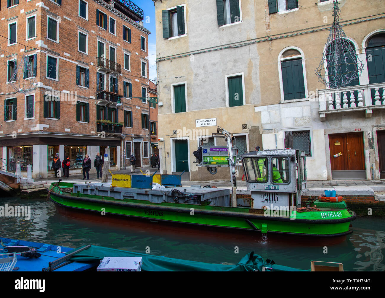 La collecte des déchets en bateau dans le canal, Venise, Vénétie, Italie Banque D'Images