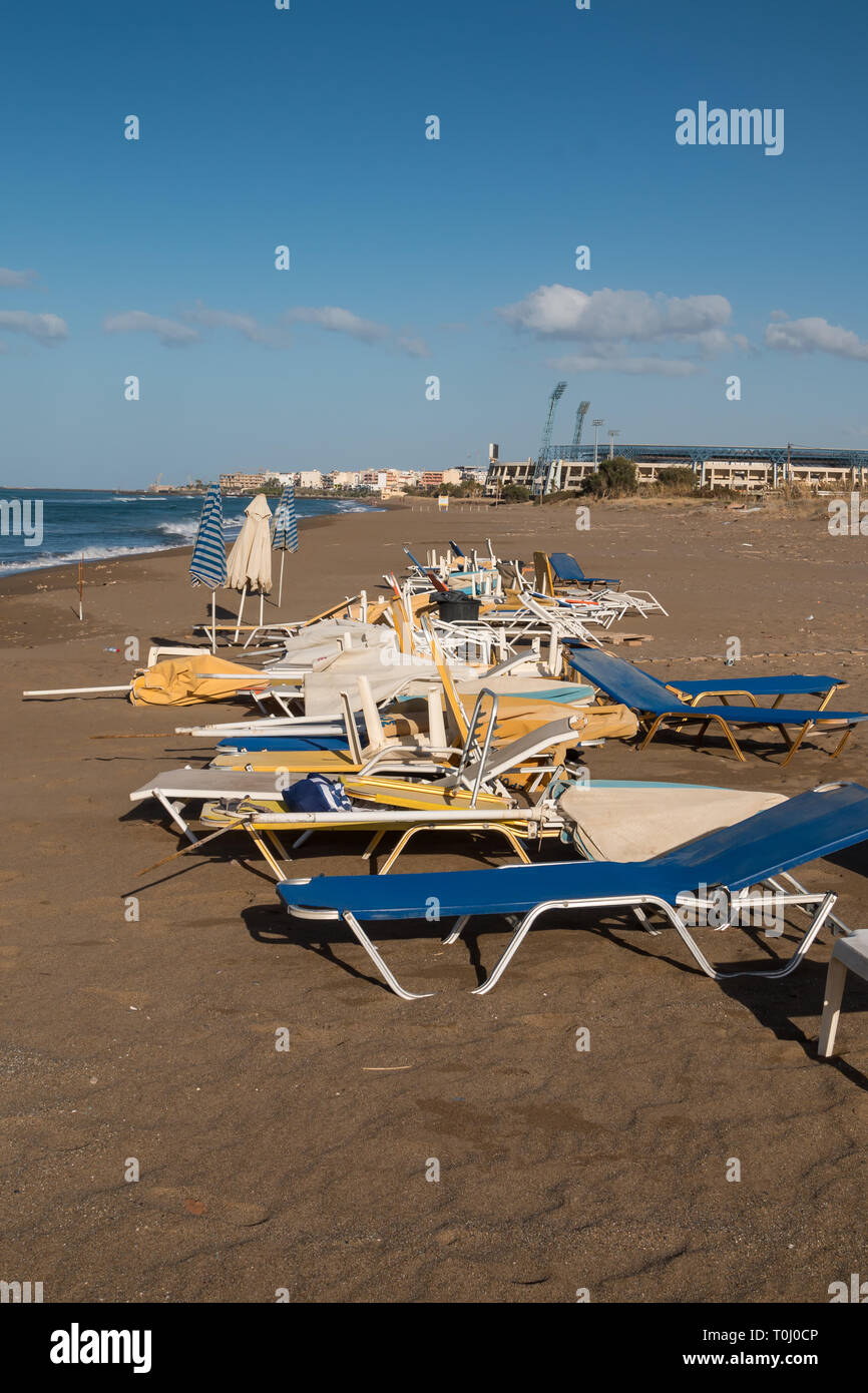 Transats malpropre après toute la journée. En début de soirée à la plage à l'automne. Le sable jaune, ville en arrière-plan. Ciel bleu avec des nuages plusieurs Banque D'Images