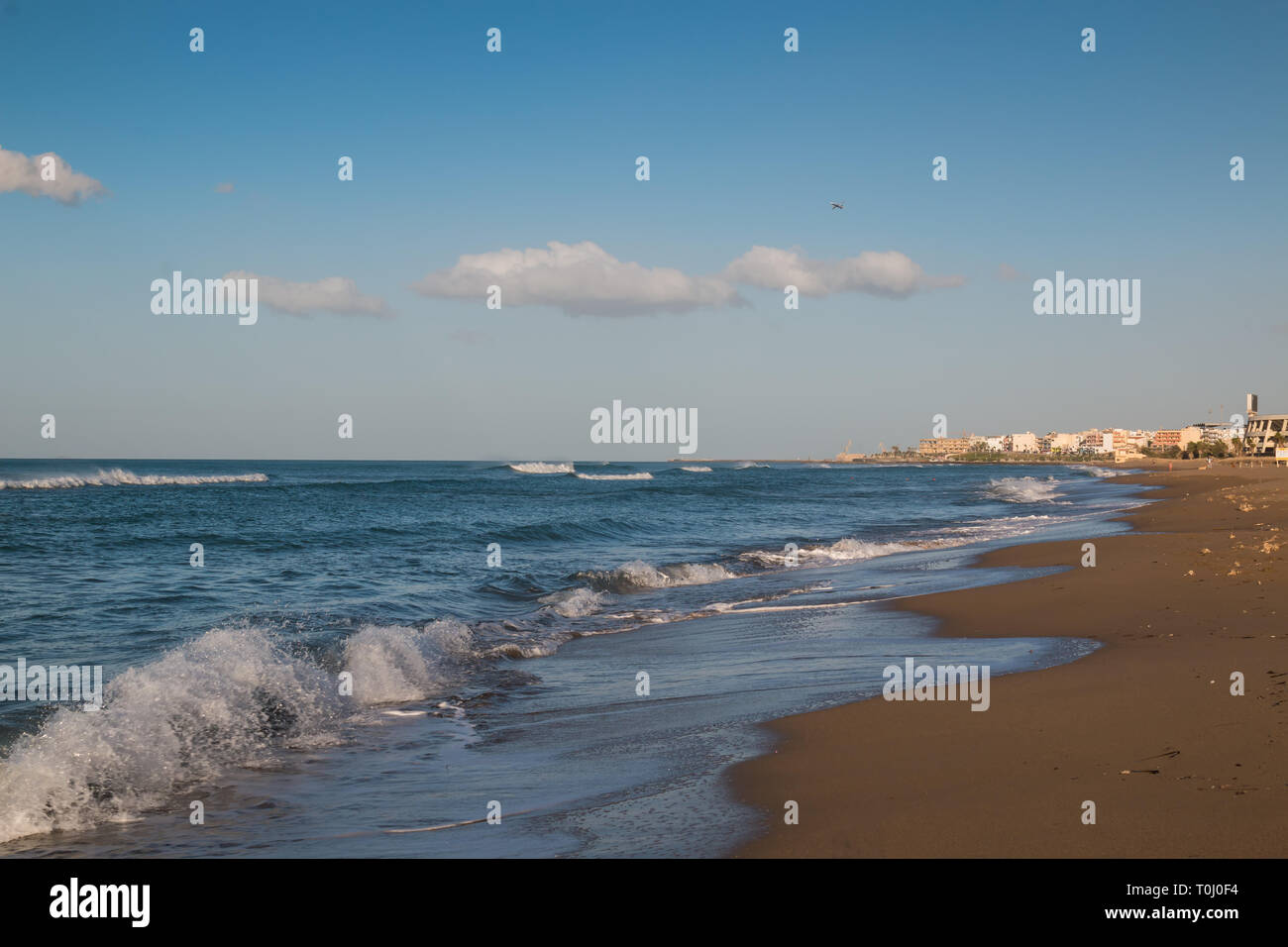 La fin de l'afteroon à la plage. Sable doré, l'eau d'un bleu profond de la mer Méditerranée avec de petites vagues. Architecture de la ville en arrière-plan. S bleu Banque D'Images