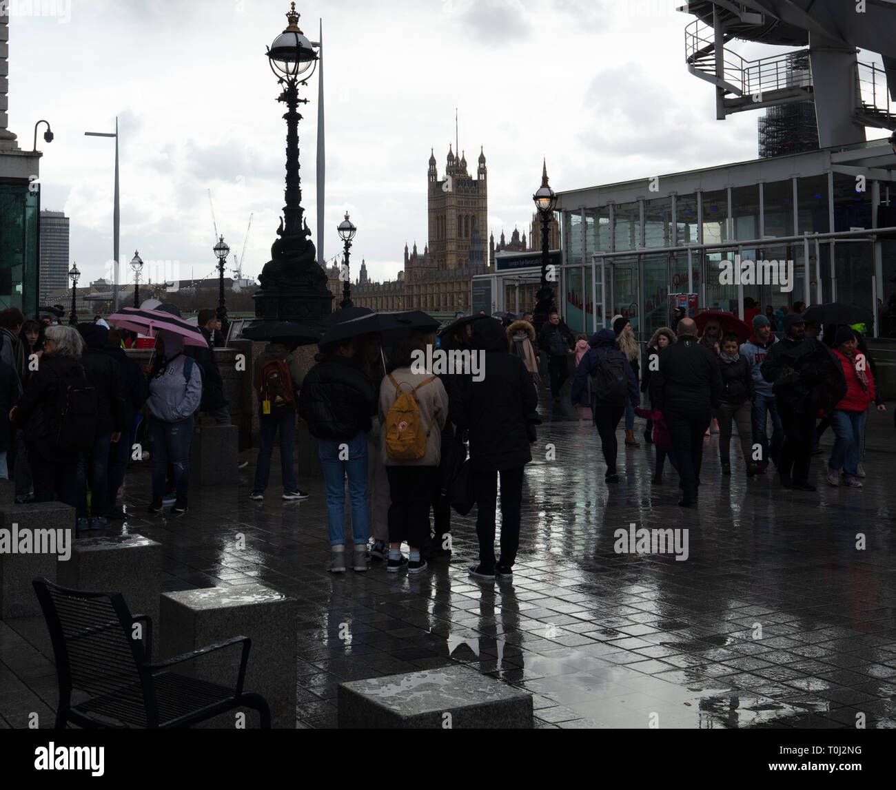 Touristes utilisent des parapluies et autres couvertures de pluie pour rester sec et humide sur ce jour humide sur la rive sud au pied du London Eye à Londres, au Royaume-Uni. Banque D'Images