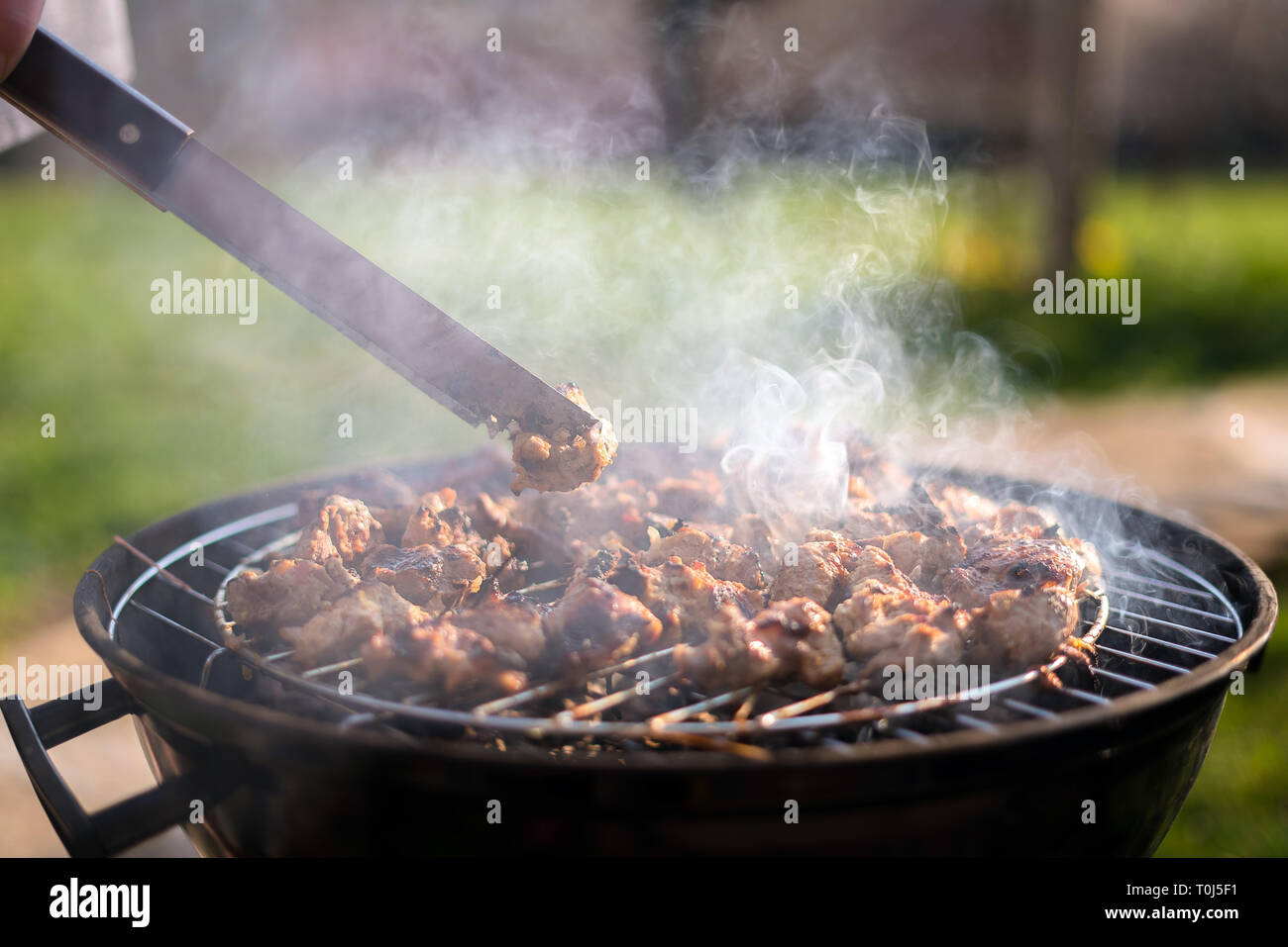 Barbecue Cuisson rencontrez sur le grill à l'extérieur dans la cour  arrière. L'heure d'été pique-nique. La viande à rôtir sur la grille de  métal sur des charbons ardents. Ajoute une saveur fumée