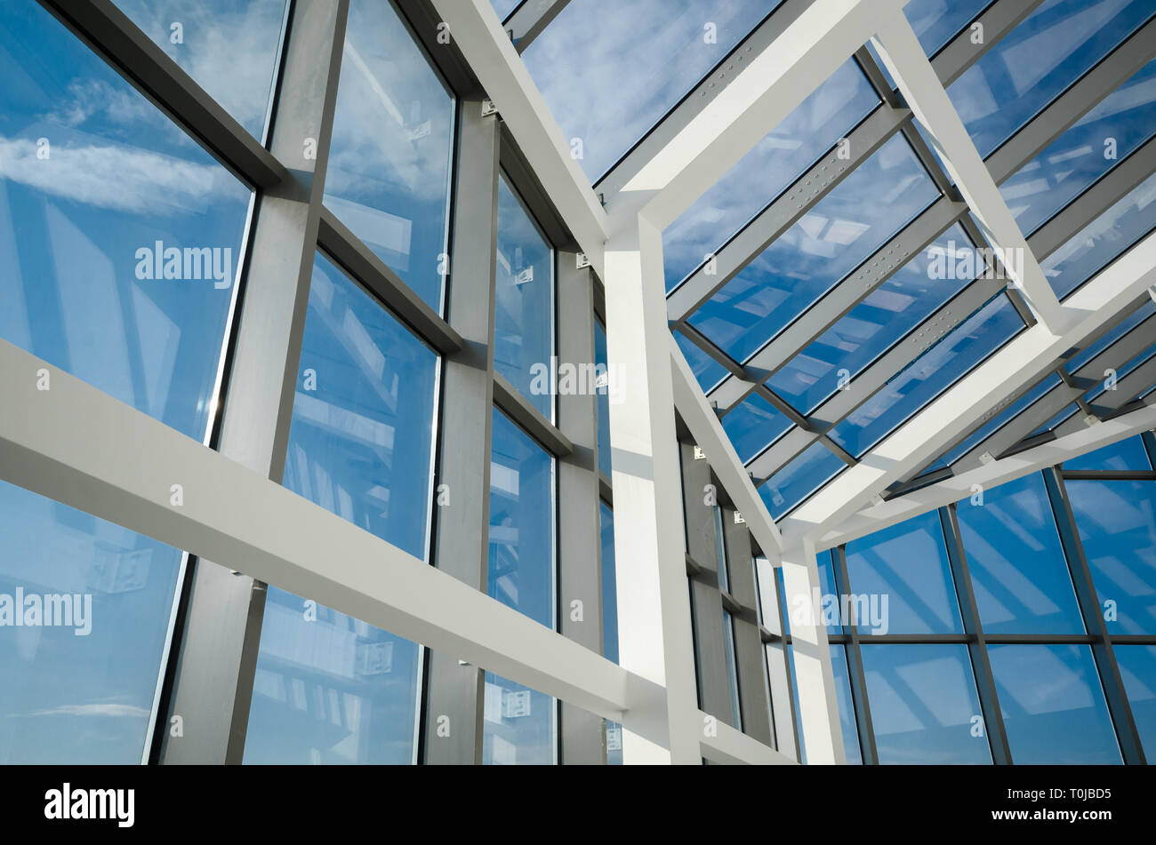 Minimalisme géométrique et plafond de verre de bâtiment de bureaux moderne avec fenêtres encadrées en aluminium contre le ciel bleu Banque D'Images