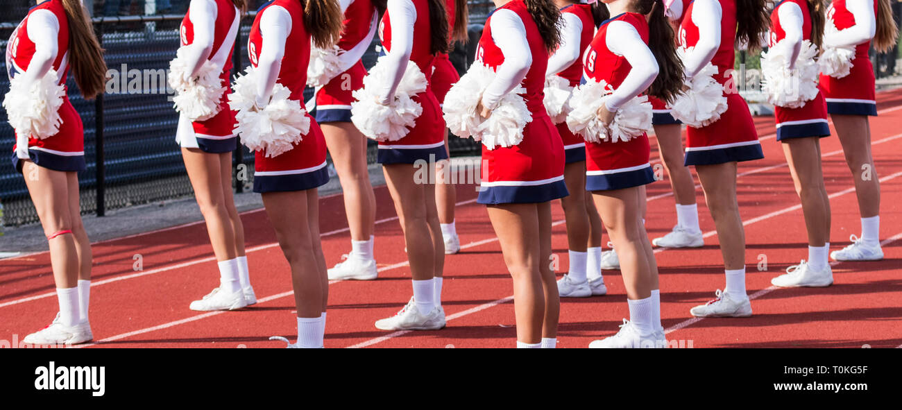 L'équipe de Cheerleading effectuant une routine en face de l'accueil des supporters à un match de football de l'école secondaire. Banque D'Images