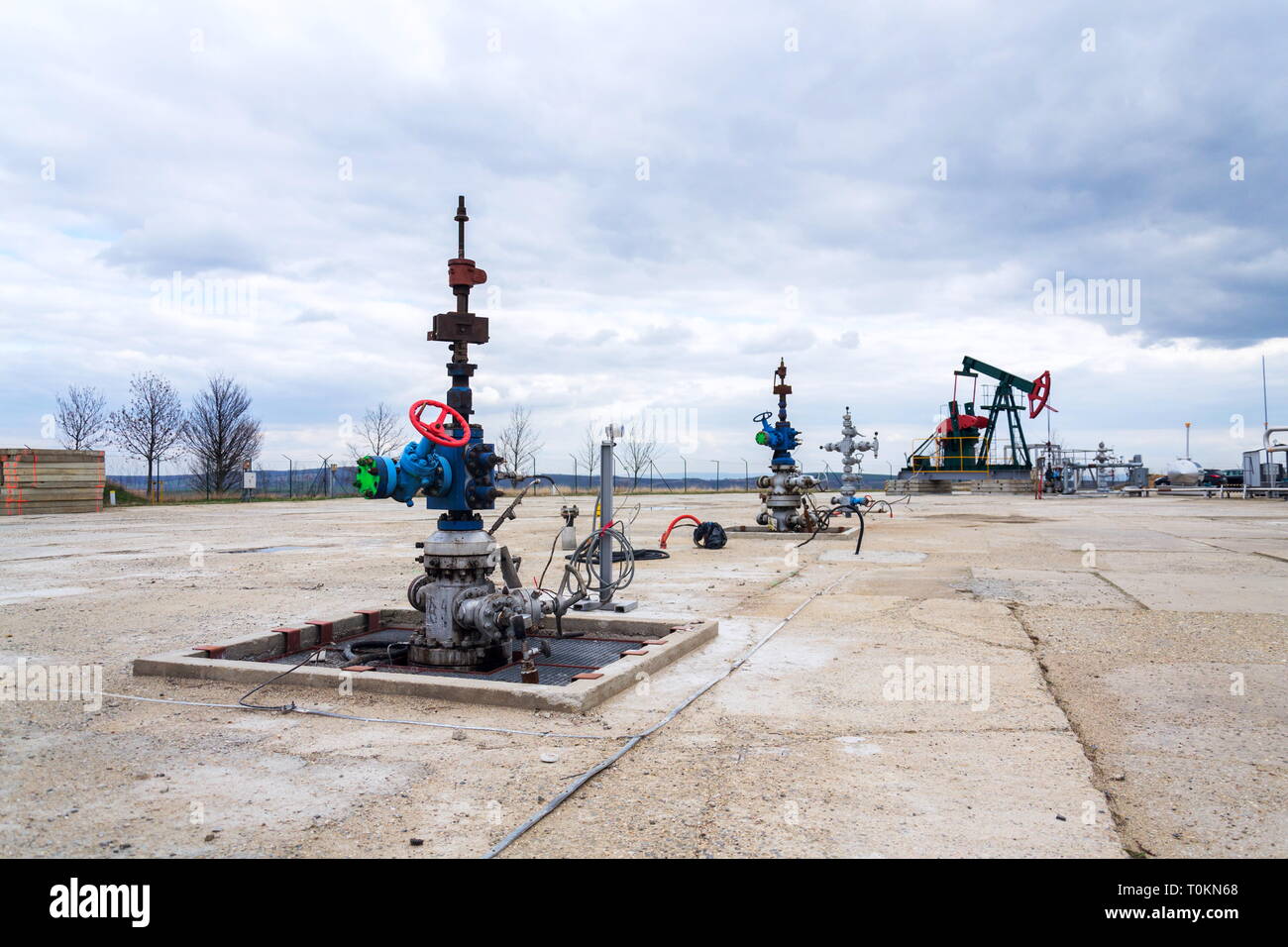 Pumpjack vert et rouge, l'huile, l'huile de cheval derrick pompant l'huile bien avec fond de ciel nuageux spectaculaire Banque D'Images