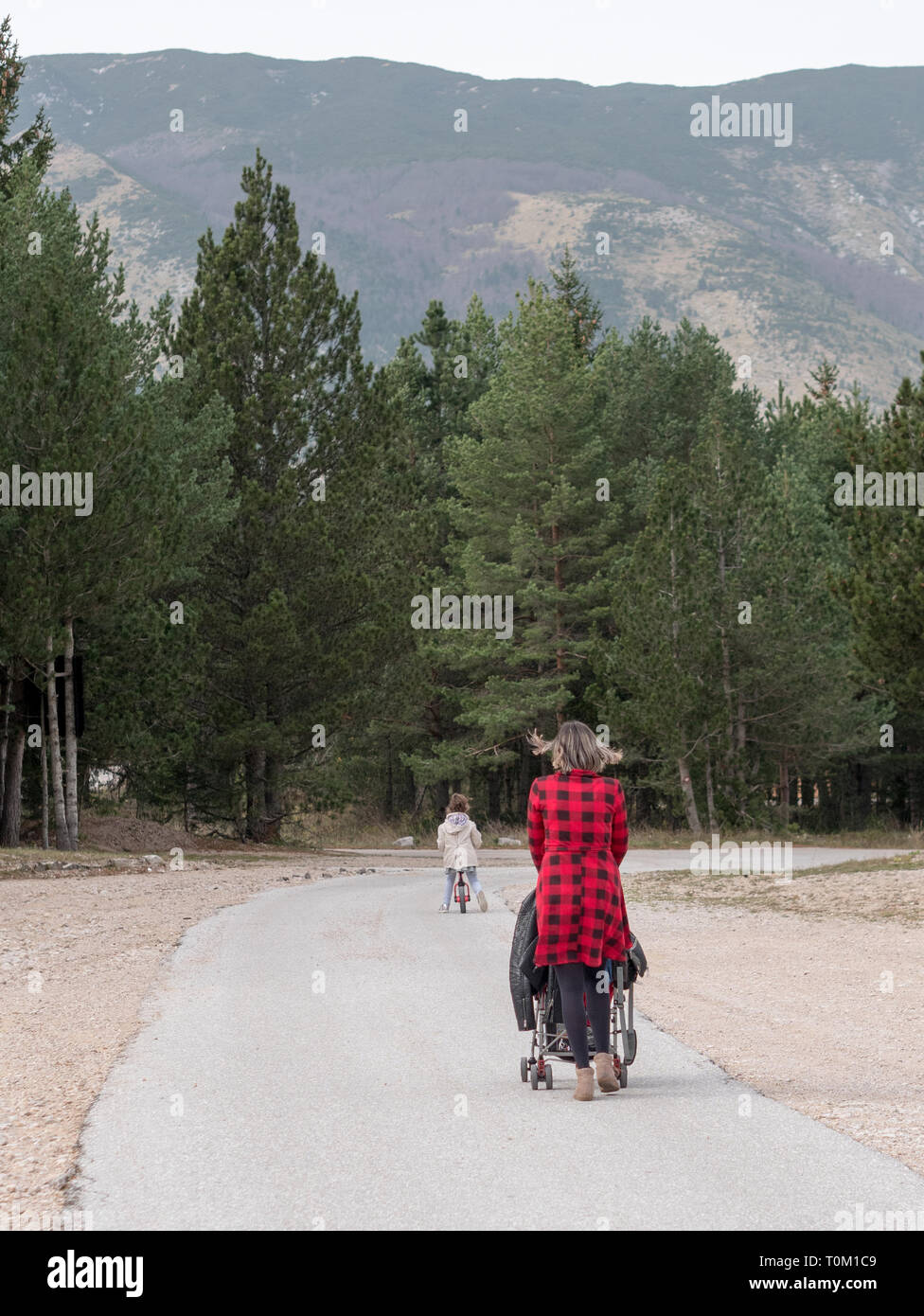 Maman marche avec poussette et petit enfant sur vélo sur route de montagne de l'arrière Banque D'Images