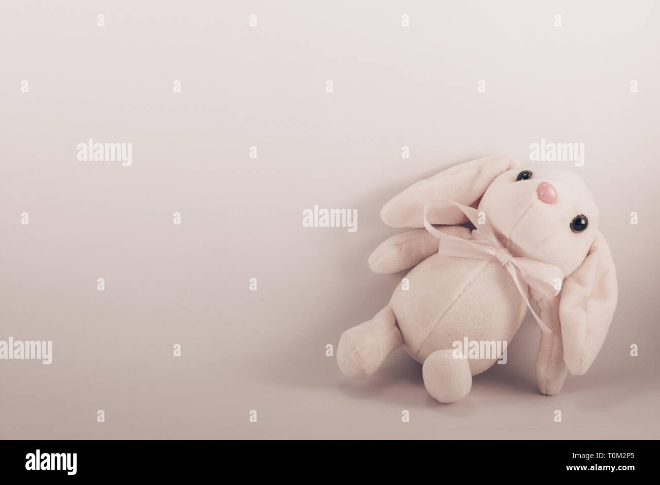Carte avec un jouet lapin blanc couché sur un fond blanc Banque D'Images