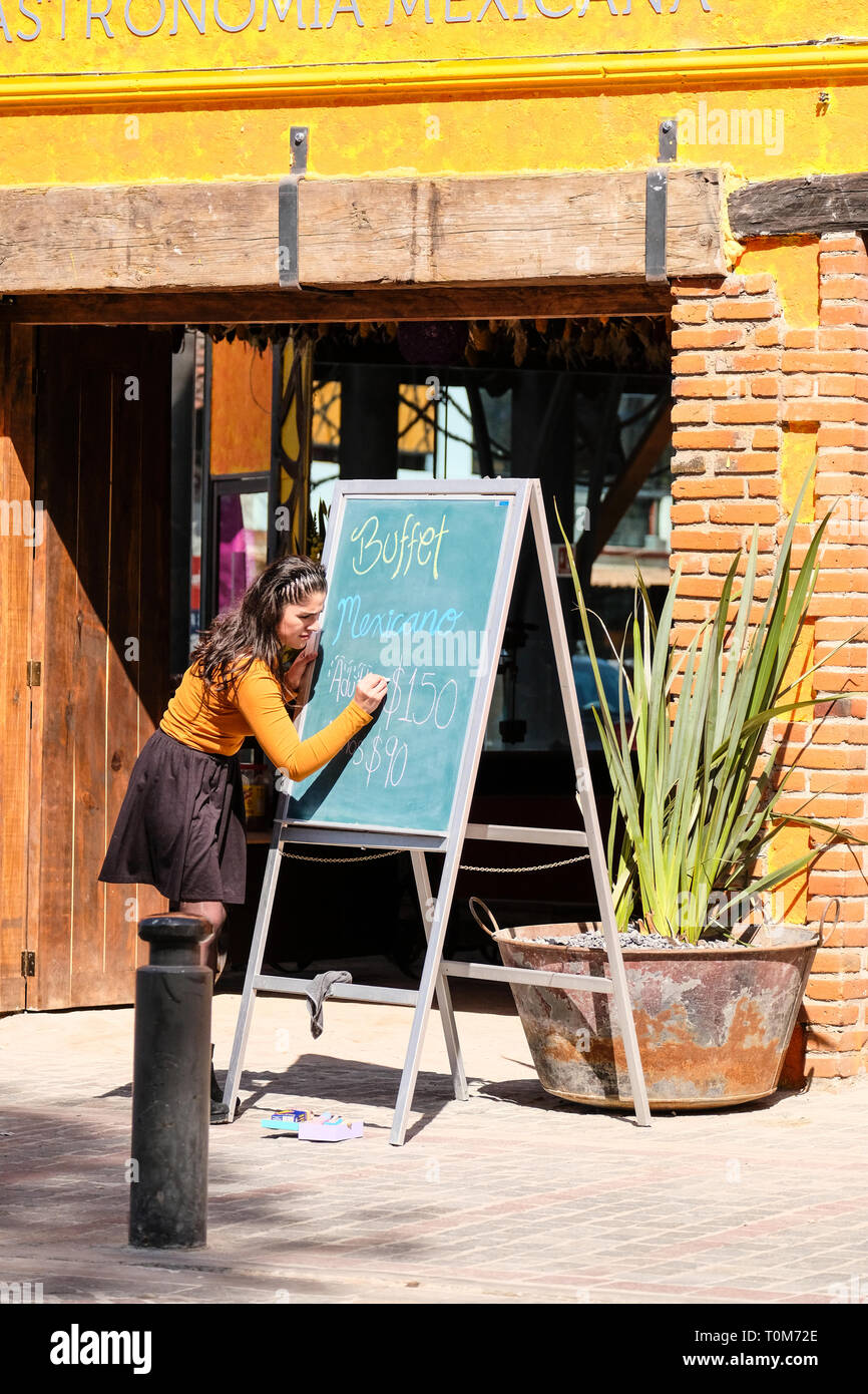 Une jolie jeune femme mexicaine menu buffet écrit à un conseil extérieur d'un restaurant mexicain à Cholula Puebla Mexique Banque D'Images