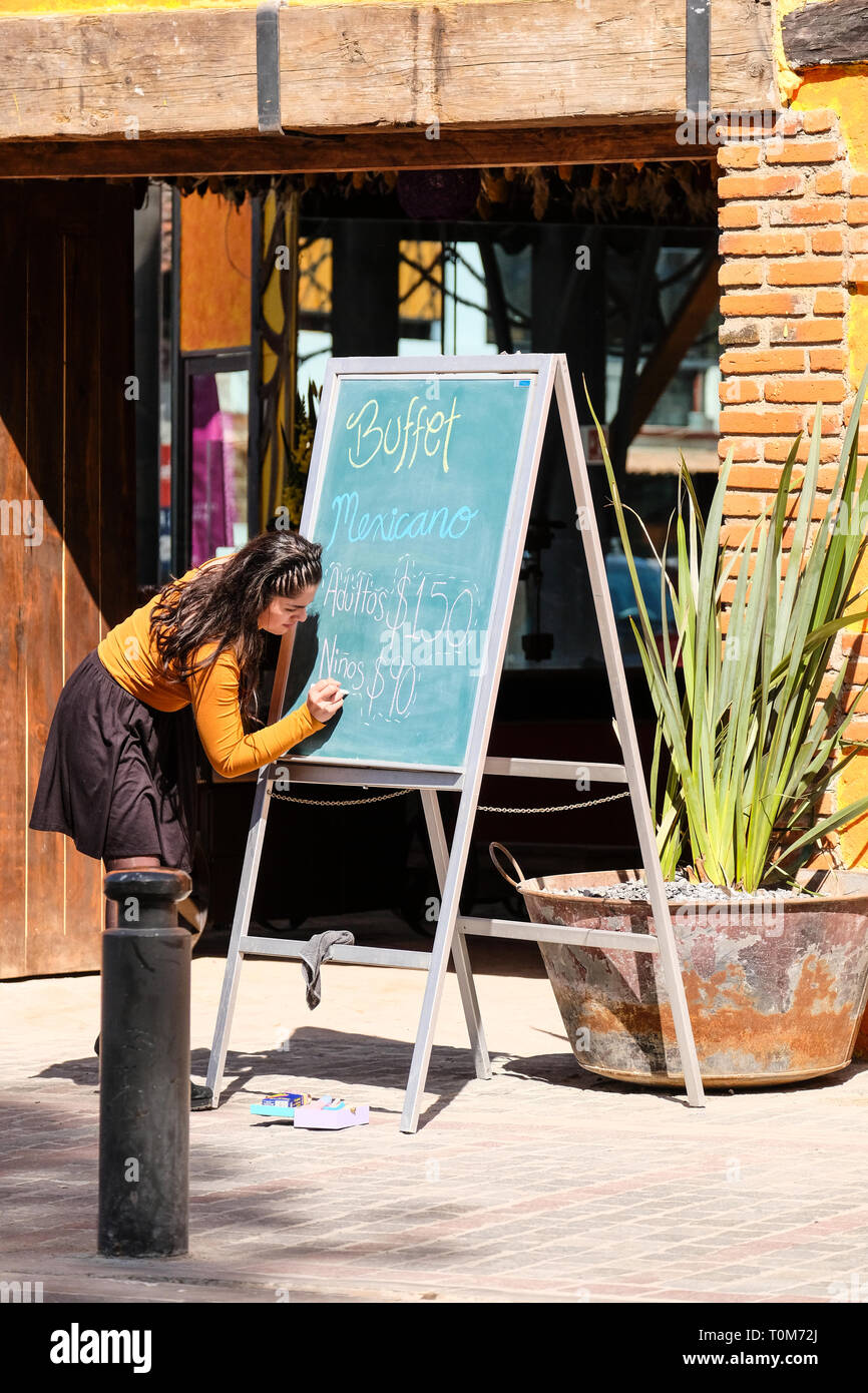 Une jolie jeune femme mexicaine menu buffet écrit à un conseil extérieur d'un restaurant mexicain à Cholula Puebla Mexique Banque D'Images