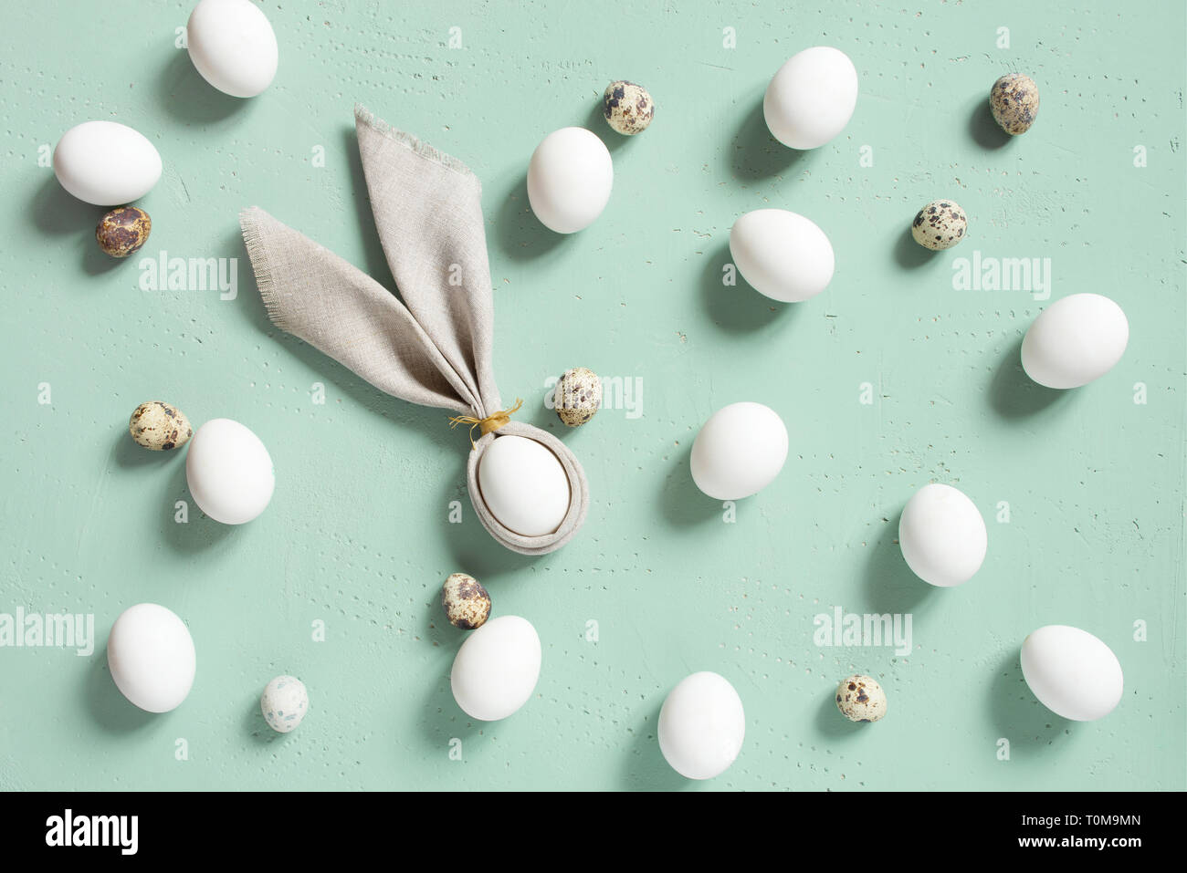 Modèle de poulet et des oeufs de cailles avec oreilles de lapin de linge serviette sur la table, texturé bleu composition Pâques, vue du dessus Banque D'Images