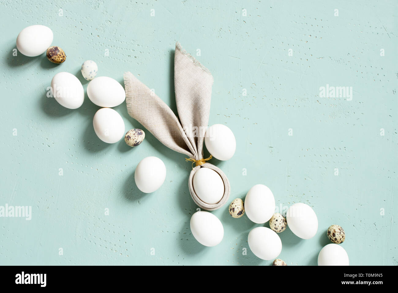 Poulet et oeufs de cailles avec oreilles de lapin de linge serviette sur la table, texturé bleu composition Pâques, vue du dessus Banque D'Images