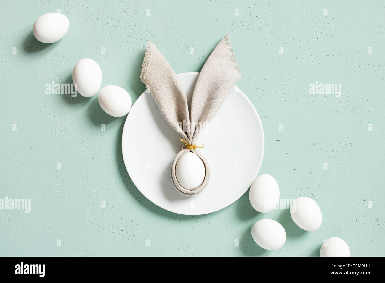 Les oeufs de Pâques avec des oreilles de lapin de linge serviette sur la table, texturé bleu Vue de dessus, copy space Banque D'Images