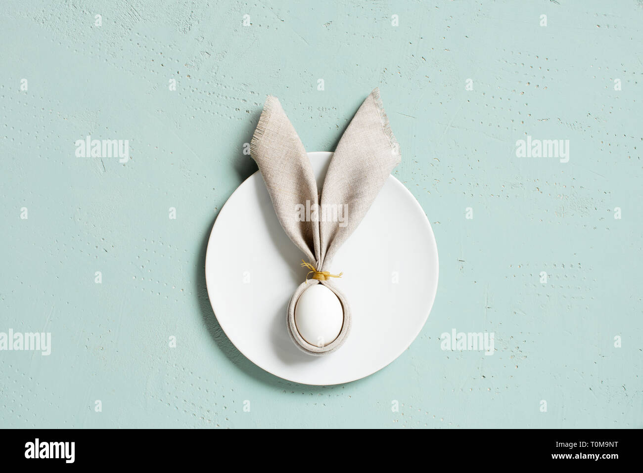 Arrière-plan avec œuf de Pâques décoré avec des oreilles de lapin de linge serviette sur la table, texturé bleu Vue de dessus, copy space Banque D'Images